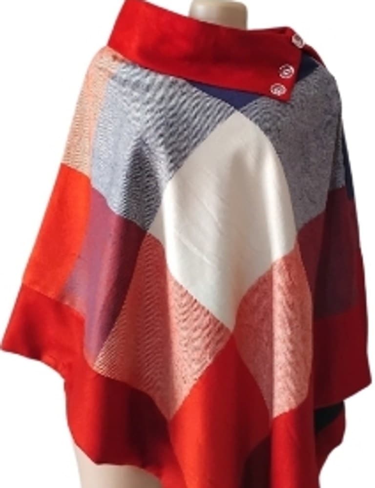 Red, navy and cream patchwork woollen poncho with buttoned red collar on a mannequin